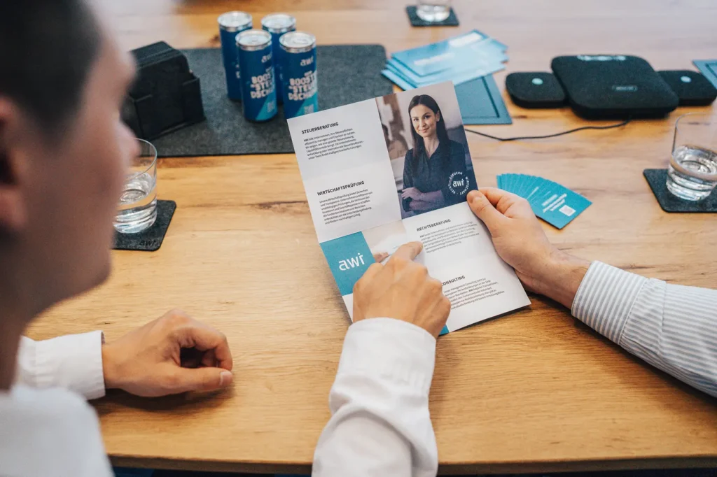 awi consulting-Flyer mit Informationen zu Steuerberatung und Wirtschaftsprüfung während eines Meetings.