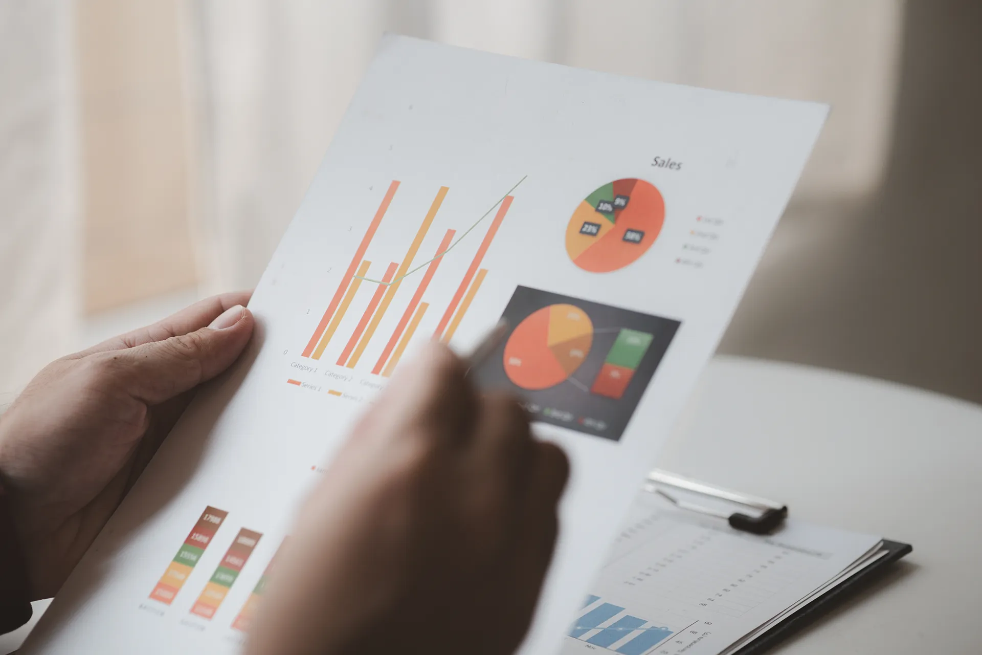 Person analysiert Verkaufsdaten auf Papier mit Balken- und Tortendiagrammen. Nachhaltigkeitsbericht für Unternehmen.