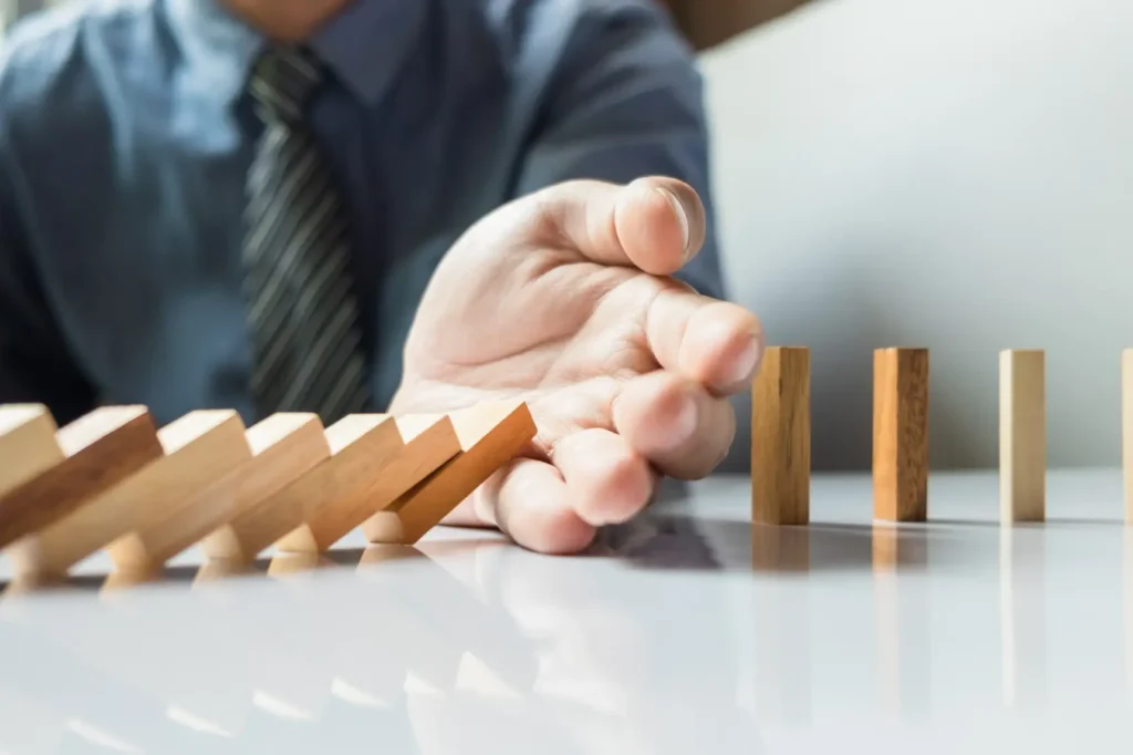 Shitstorm-Management im Unternehmen: Hand stoppt Dominoeffekt als Symbol für professionelle Krisenkommunikation und Reputationsschutz.