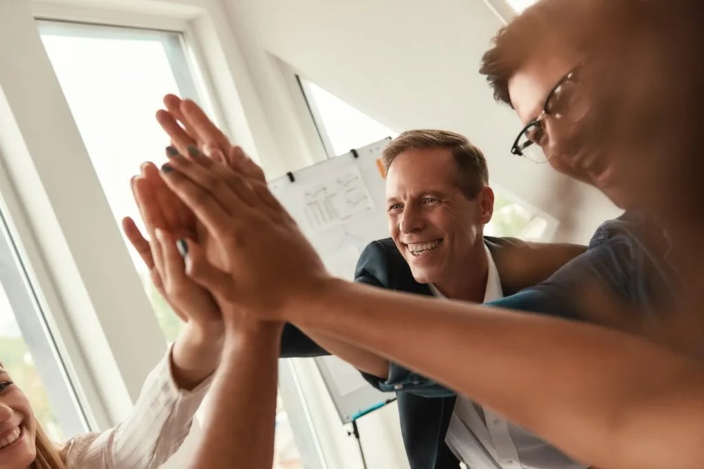 Unternehmenskultur: Der unterschätzte Erfolgsfaktor 1 Team von Fachpartnern legt die Hände übereinander im Büro, Symbol für Zusammenarbeit und Partnerschaft rund um smarte Stromsteuerung und Stromintelligenz App.